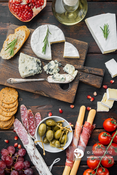 Italian snacks, meat cheese, herbs, on dark wooden background, top view