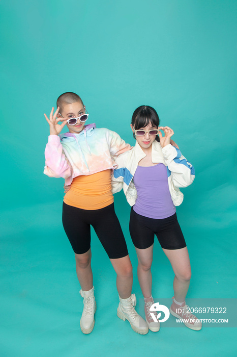 Studio portrait of two smiling girls wearing sunglasses