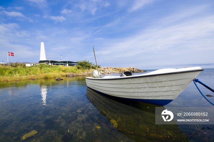 Fishing boat moored on the coast of Baltic Sea in Allinge, Bornholm, Denmark. Chimney of smokehouse in the background.