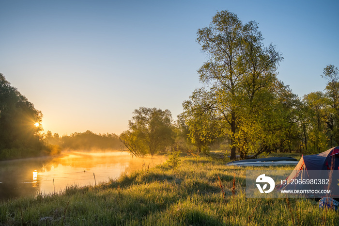 Landscape with camping tent and kayak on the river at sunrise