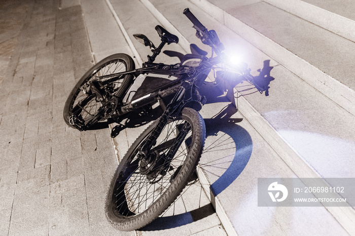 A bicycle parked at night on a city street with a light lamp on