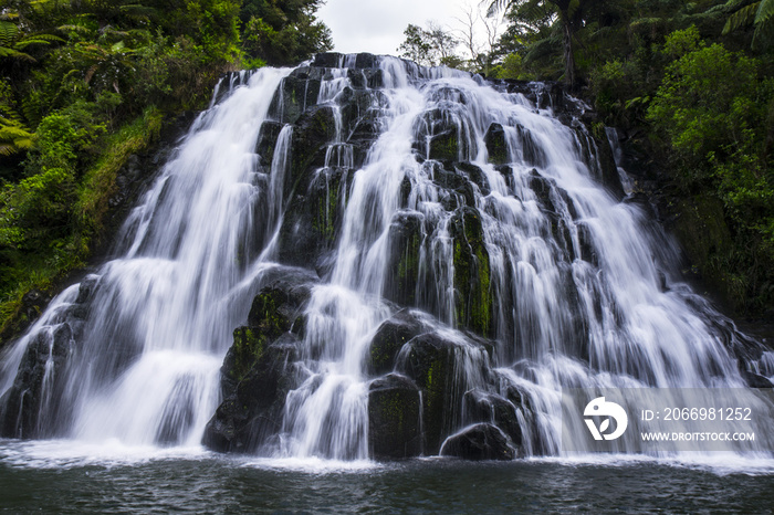 Travel/Exploring beauty of New Zealand. Owharoa Falls, Waihi, favourite/popular nature attraction in North Island. Long exposure falling water. Green, outdoor background.