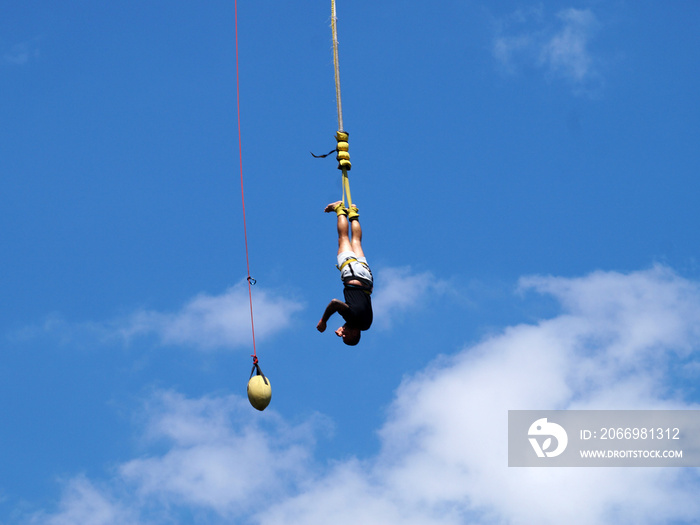 a man jumping on an elastic band from a bridge catches a lifting cable