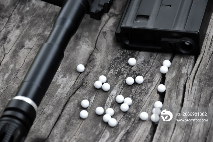 Closeup of white plastic bullets of airsoft gun or bb gun on wooden floor, soft and selective focus on white bullets.