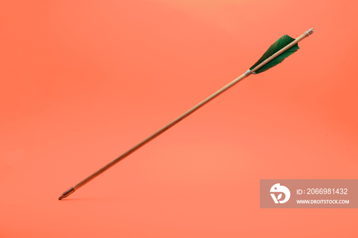 Old green wooden arrow on a beautiful peach background.