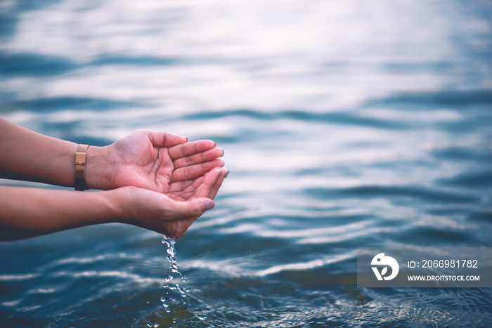 The hand that touches the blue water. The pool is clean and bright. With a drop of water on the water.