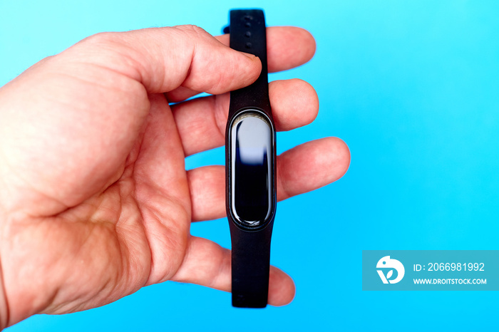 Wristband watch, in a male hand on a blue background. Health monitoring device.