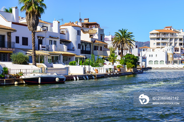 Houses next to the canals of the sea and boats docked in the docks next to the houses in Ampuriabrava, Gerona, Spain.