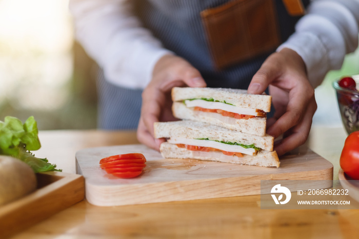 Closeup image of a female chef cooking and holding a piece of whole wheat sandwich in kitchen