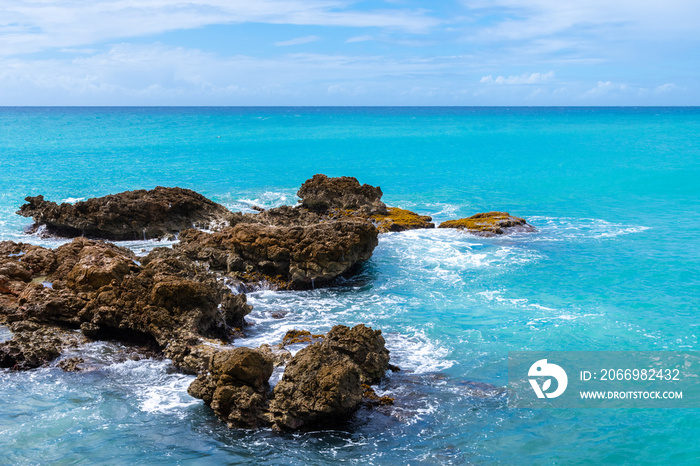 Tropical Caribbean island ocean view with water foam against large sea rocks. Endless pristine water in sunny scenic paradise.