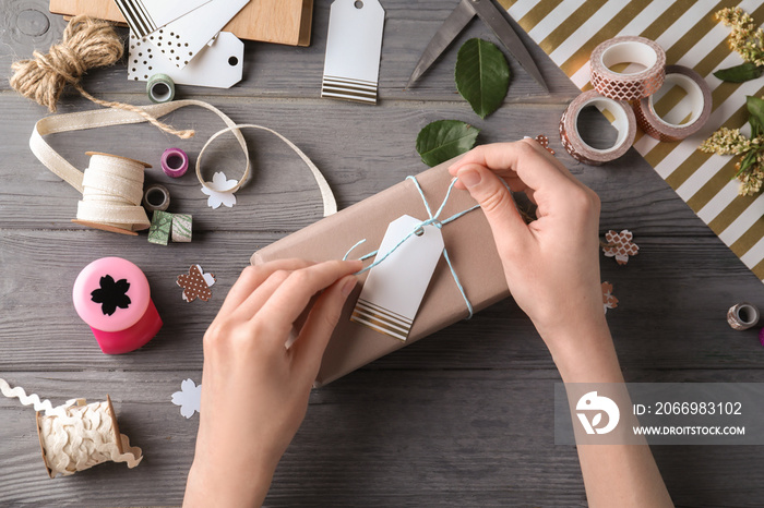 Woman packing beautiful gift on wooden background