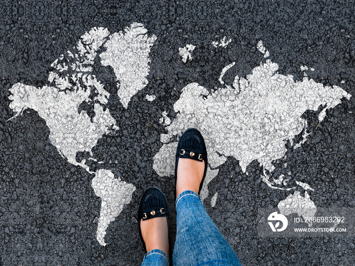 World map on an asphalt road and woman in shoes