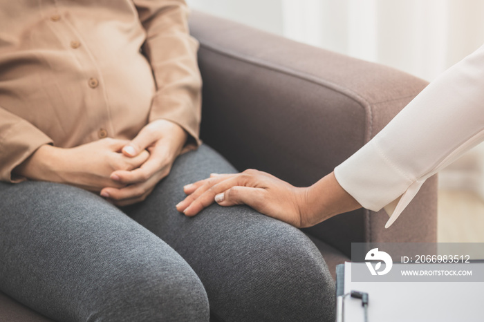 Asian young woman suffers from mental who needs to therapy with a psychologist while sitting on couch to consult, psychiatrist has encouragement the patient by touching to make her feel relaxed.