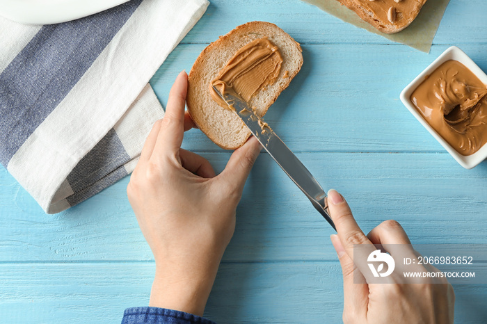 Woman spreading peanut butter on toast over table