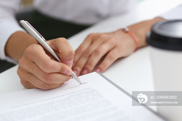 Female hand holding silver pen ready to make note in opened notebook sheet. Businesswoman coffee cup workspace make thoughts records at personal organizer, white letter collar conference, signature