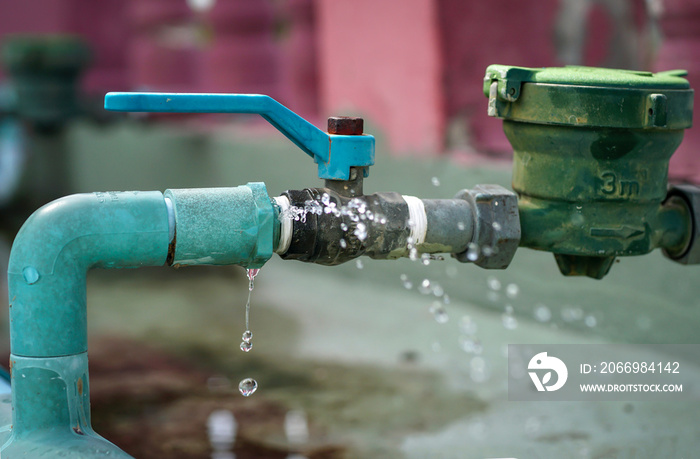 Water leaks water drop from a long-used blue plumbing pipe. Selective focus to Water leaks.