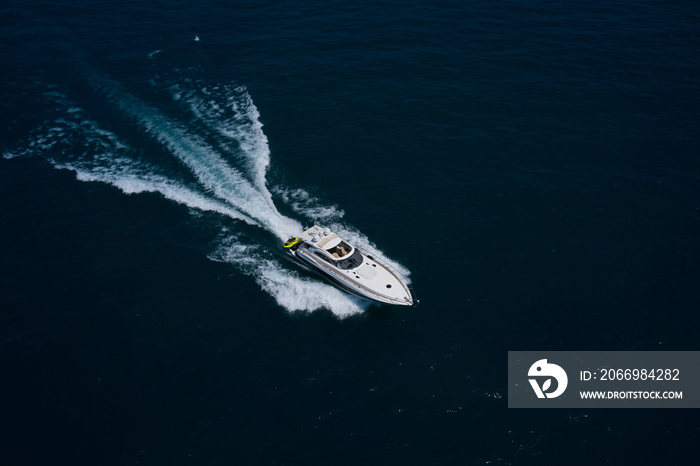 Large white yacht on the water in motion top view. The yacht is fast moving on dark water.