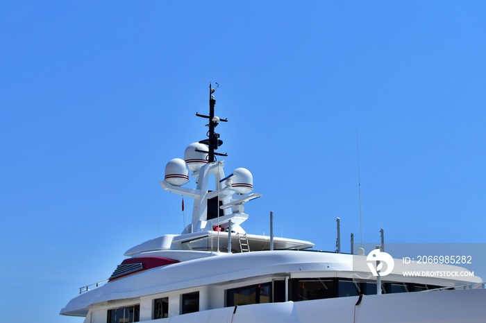 Ship in the harbor. Upper deck of modern marine yacht with radar equipment against blue sky