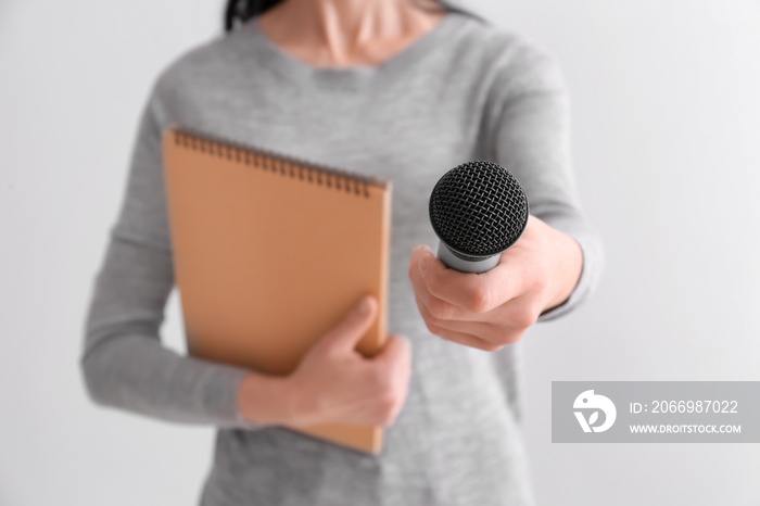 Female journalist with microphone on light background, closeup