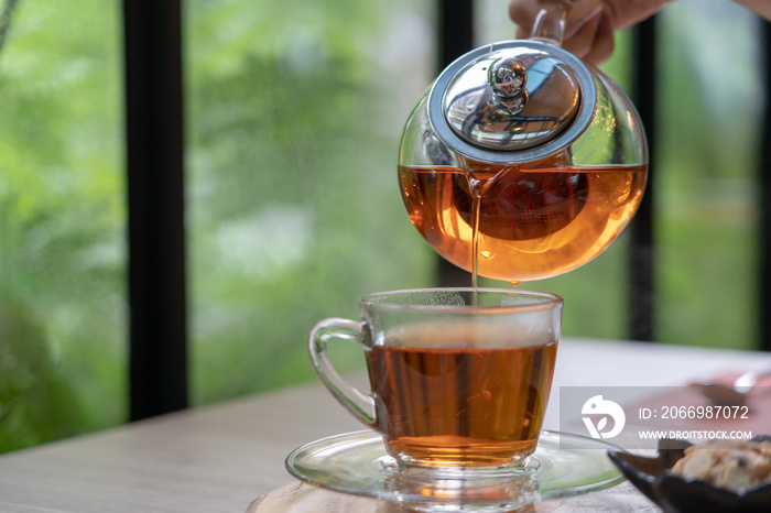 Tea set in clear glass jug and dessert. During leisure time drinking aromatic tea with delicious cookies. Is a relaxed feeling.