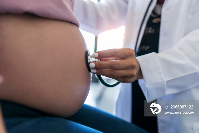 Woman gynecologist checking the heartbeat baby of her pregnant patient in the clinic.