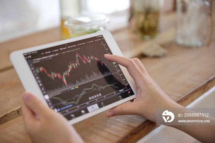 Woman hand using a tablet for Stock exchange trading online in the coffee shop, business concept