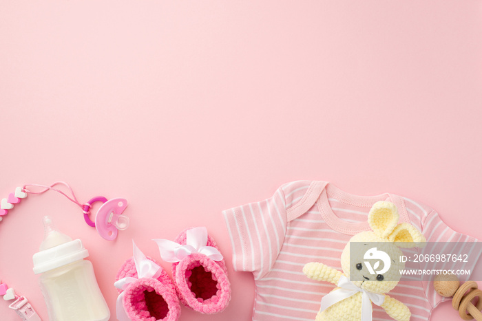 Baby accessories concept. Top view photo of pink shirt booties pacifier chain knitted bunny toy wooden rattle and bottle on isolated pastel pink background with copyspace