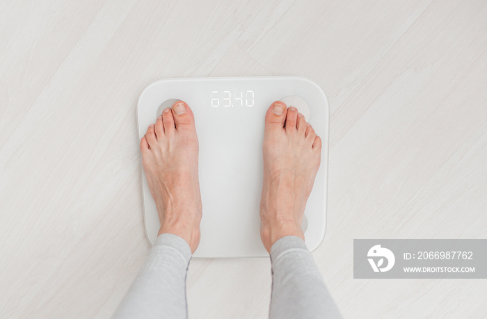 Woman is standing on bathroom scales. Weight measurement and control. Concept of healthy lifestyle, dieting and fitness