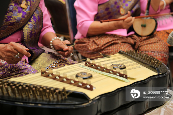 Women with thai national dress playing dulcimer in Thai traditional music show.