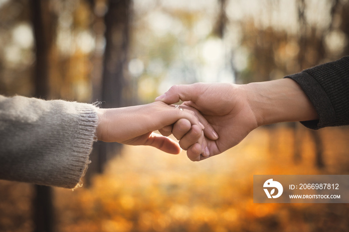 Close-up of a couple in love holding hands while walking. Selective focus.