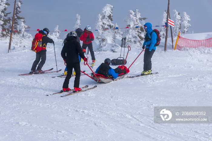 Ski rescue team with slide stretcher, brings help to ski during bad weather conditions.