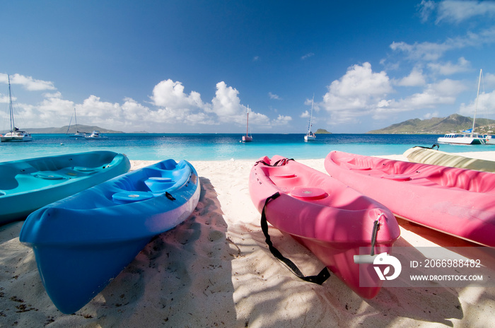 Colorful kayaks on tropical sandy beach. Boats for rafting on water. White sand, turquoise ocean water and blue sky at exotic Palm Island. Saint Vincent and Grenadines, West Indies