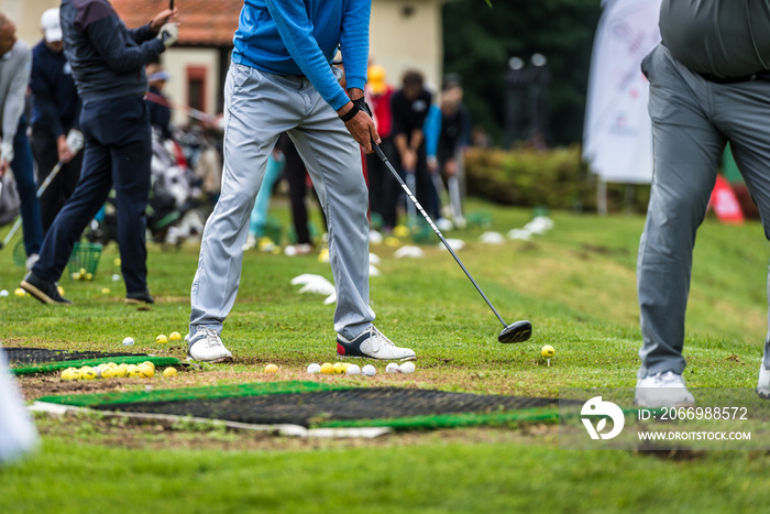 Golfer legs at golf tournament practice swing with golf club.