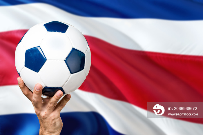 Costa Rica soccer concept. National team player hand holding soccer ball with country flag background. Copy space for text.