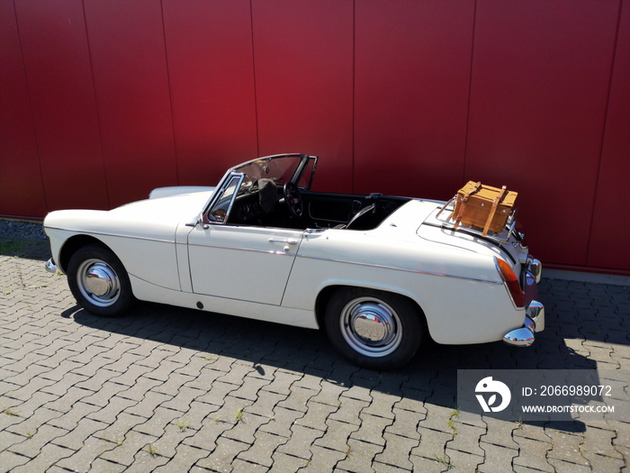 Weißer offener englischer Roadster und Sportwagen der Sechzigerjahre mit Gepäckbrücke und Koffer im Sonnenschein beim Oldtimertreffen im Oldtimer-Park Lippe in Lage bei Detmold in Ostwestfalen-Lippe