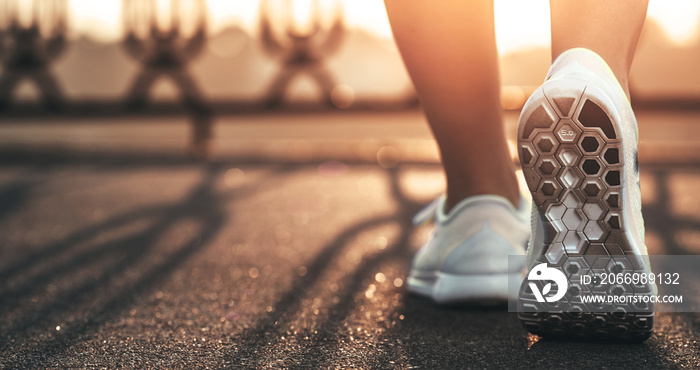 Runner woman feet running on road closeup on shoe. Female fitness model sunrise jog workout. Sports healthy lifestyle concept.