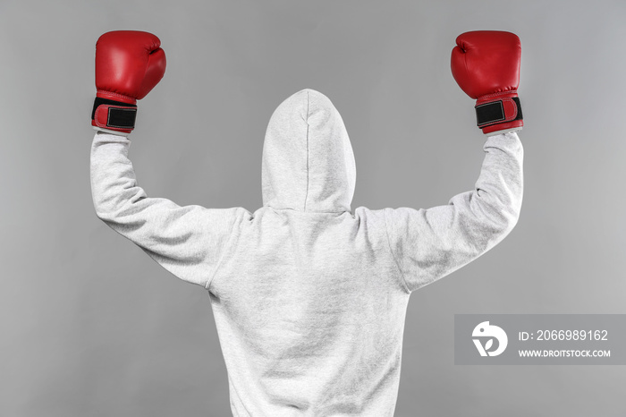 Boxer in hoodie posing on grey background