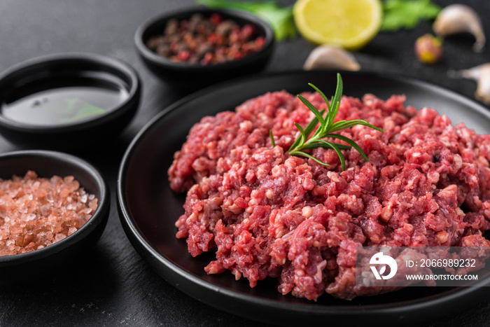 Fresh minced meat ground beef on a black plate against stone background