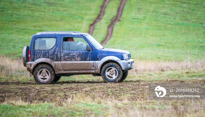 4x4 off-road vehicle driving across mud and water-logged terrain, Wilts UK. Suzuki Jimny