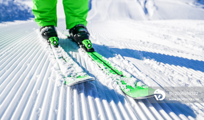 Skis and boots detailed from front view. New groomed piste or slope. Lines in snow with ski.