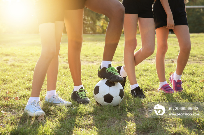 Kids legs with football ball on field