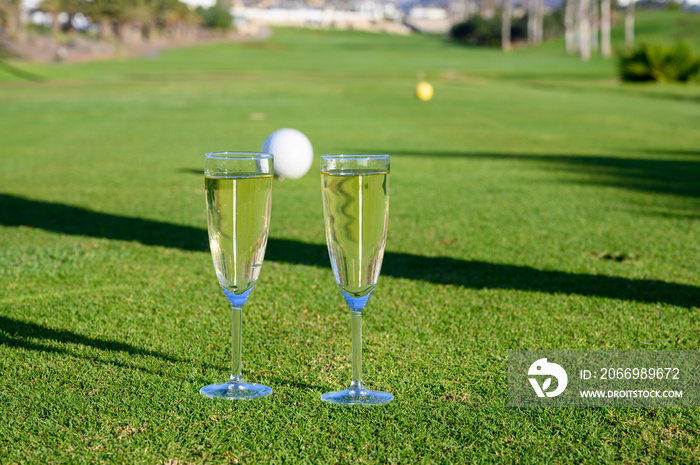 Two glasses with  bubbles white champagne or cava wine served on green golf club grass with mountains view during golf competition event or celebration