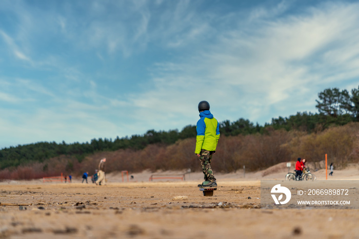 Man in the helmet riding his electric onewheel board on the beach