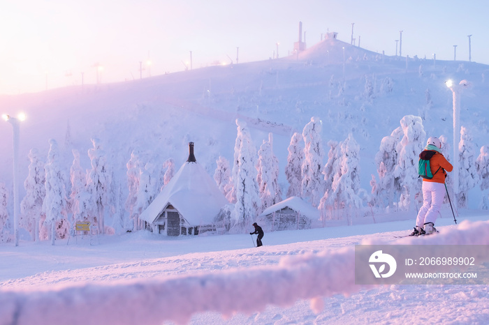 A group of skiers slide from the top of the mountain in the sun. Early morning. sunrise. Kuusamo Ruka. Finland. Panorama view.