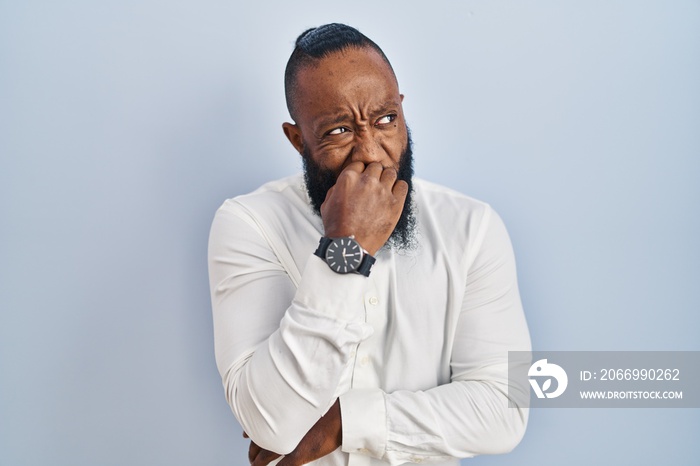 African american man standing over blue background looking stressed and nervous with hands on mouth biting nails. anxiety problem.