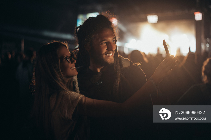 Couple taking selfie with a smartphone on a music festival