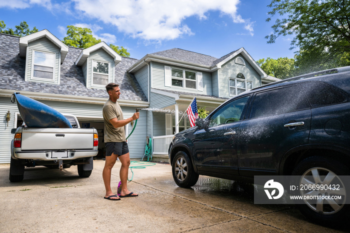 Air Force service member washes his vehicles with his sons in the driveway.