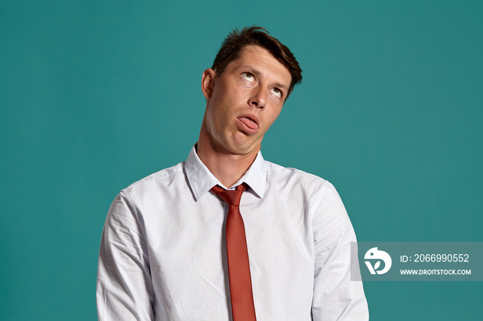 Young man in a classic white shirt and red tie posing over a blue background.