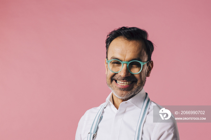 Mature happy man in apron and with blue glasses smiling at camera