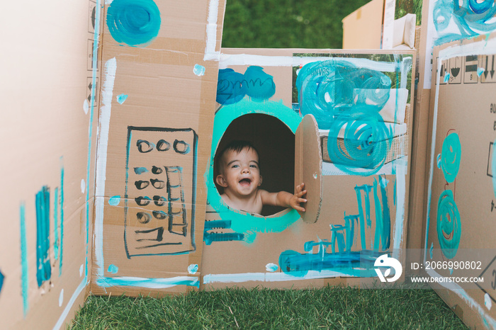 A happy baby in a painted cardboard box.